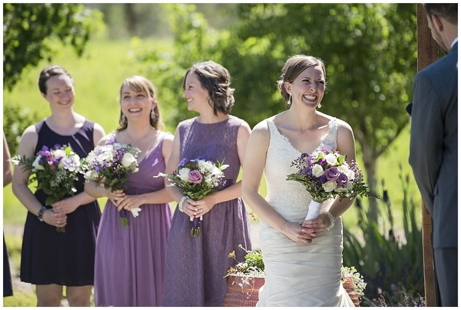 bride laughs during open air chapel wedding ceremony at spring Denver Botanic Gardens at Chatfield Wedding by Denver Botanic Gardens wedding photographer Jennie Crate