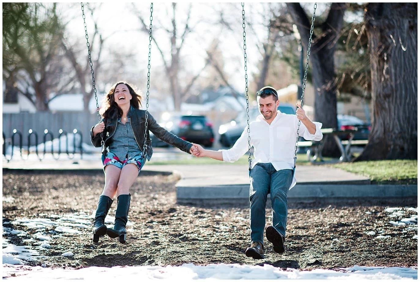 engaged couple playing on swingsets in small town colorado photo