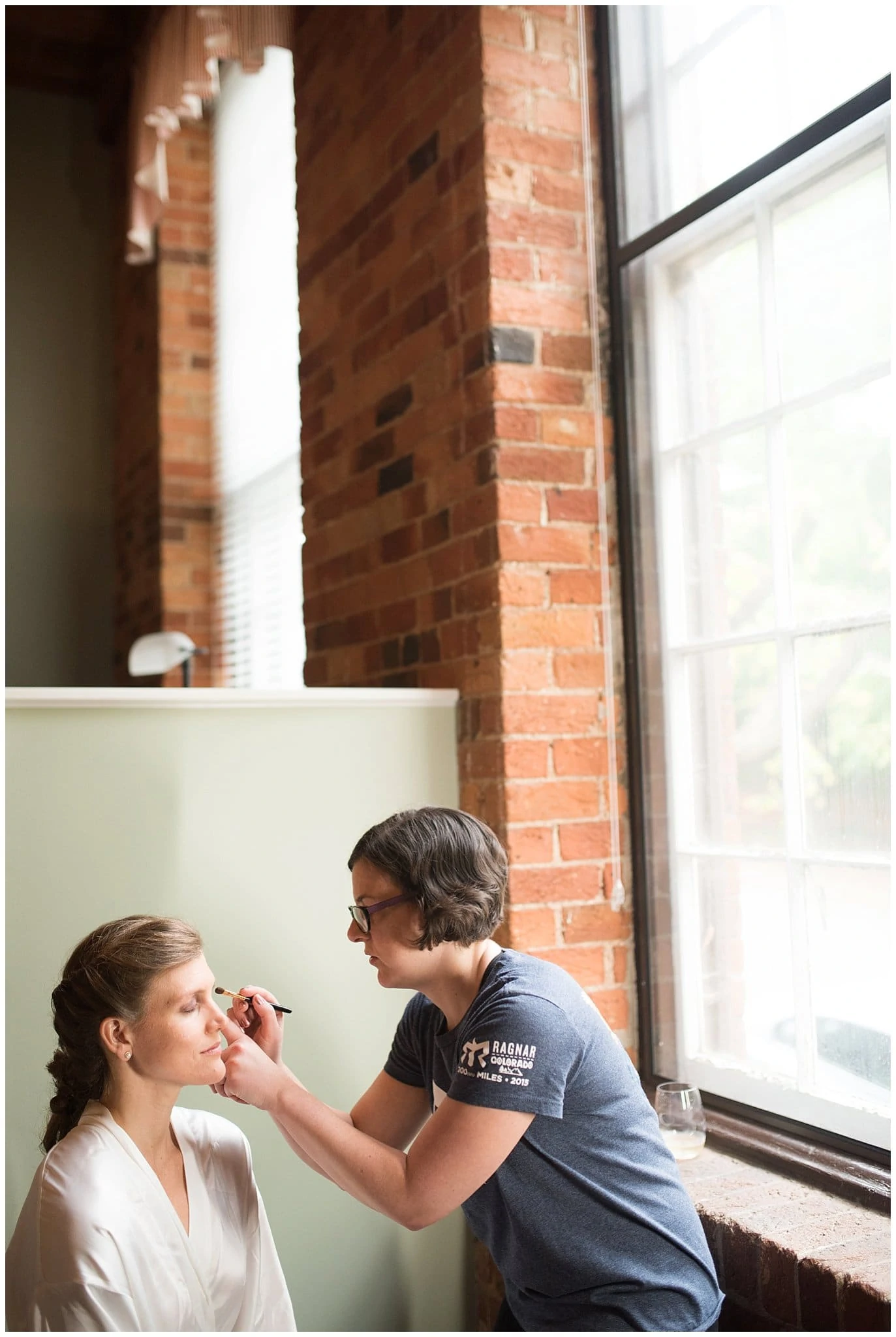 bride getting make-up done by window photo