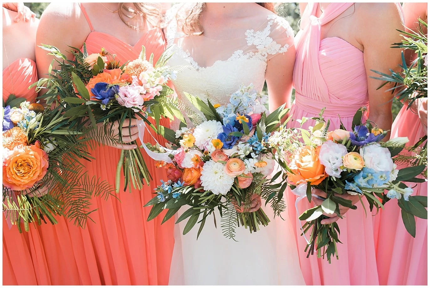 bridesmaids in mismatched coral dresses with mountain flowers photo