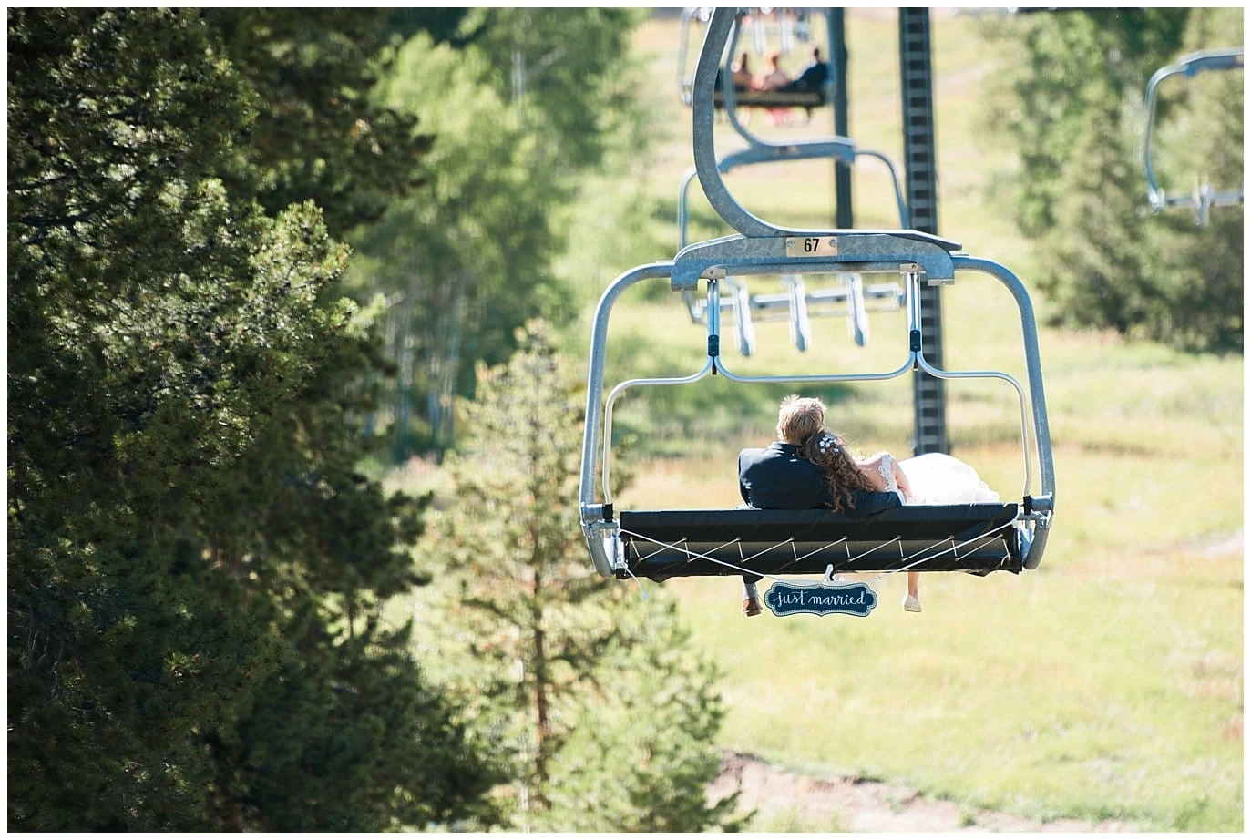 bride and groom riding chair lift down colorado mountain photo