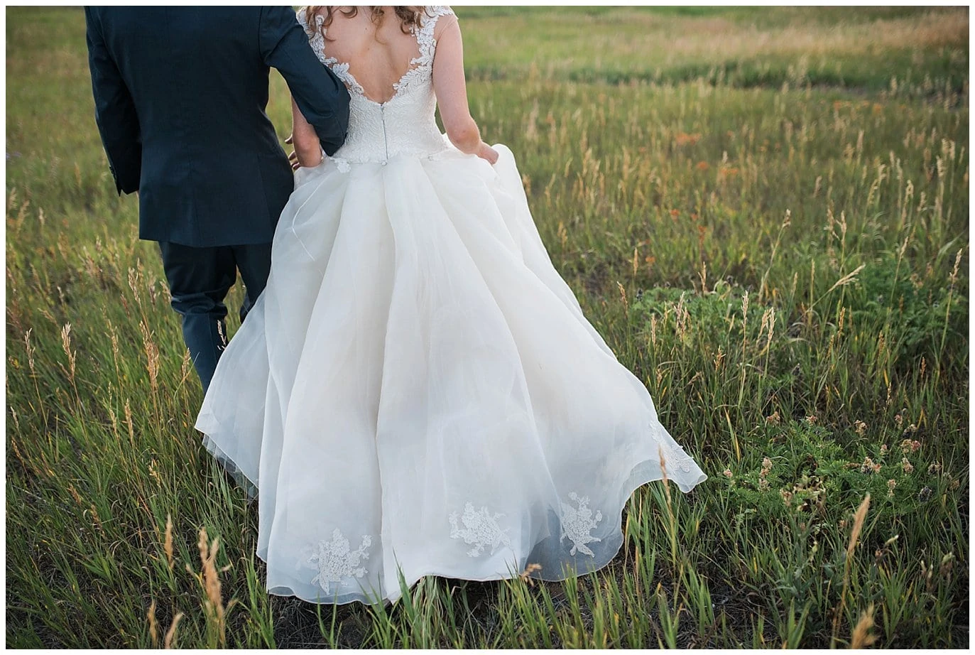 bride walking through field in custom lace wedding dress photo
