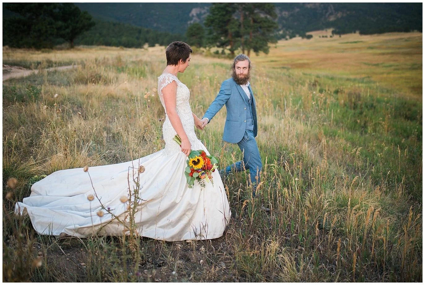 couple walking through colorado field on wedding day photo