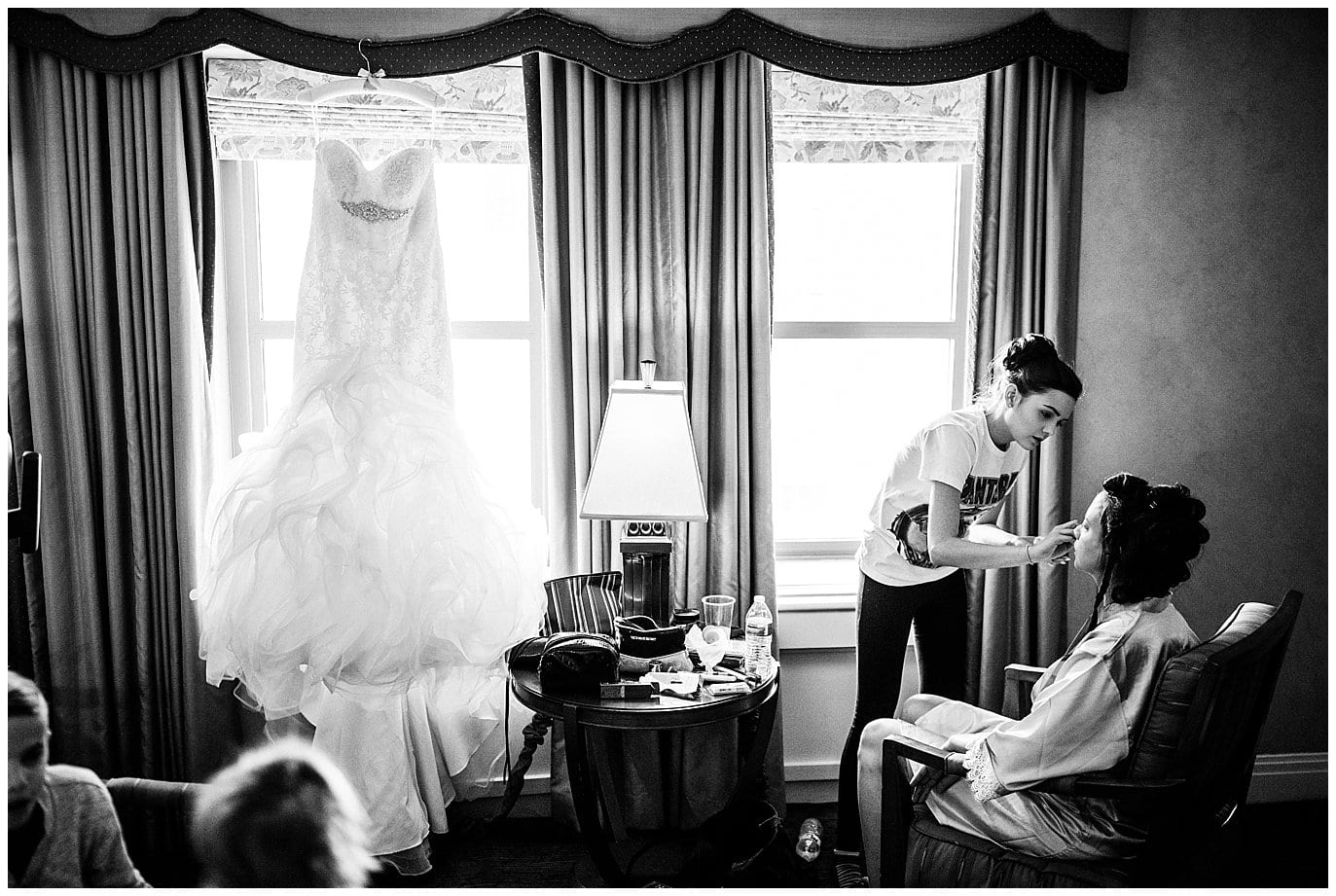 bride getting make up on with dress silhouetted in window photo