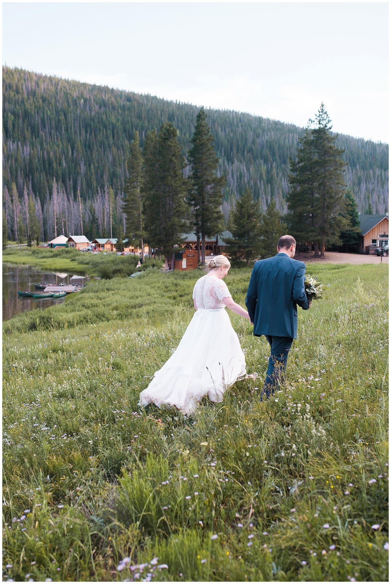 groom holding brides hand as they walk back to reception at sunset at Piney River Ranch wedding by Vail wedding photographer Jennie Crate photographer