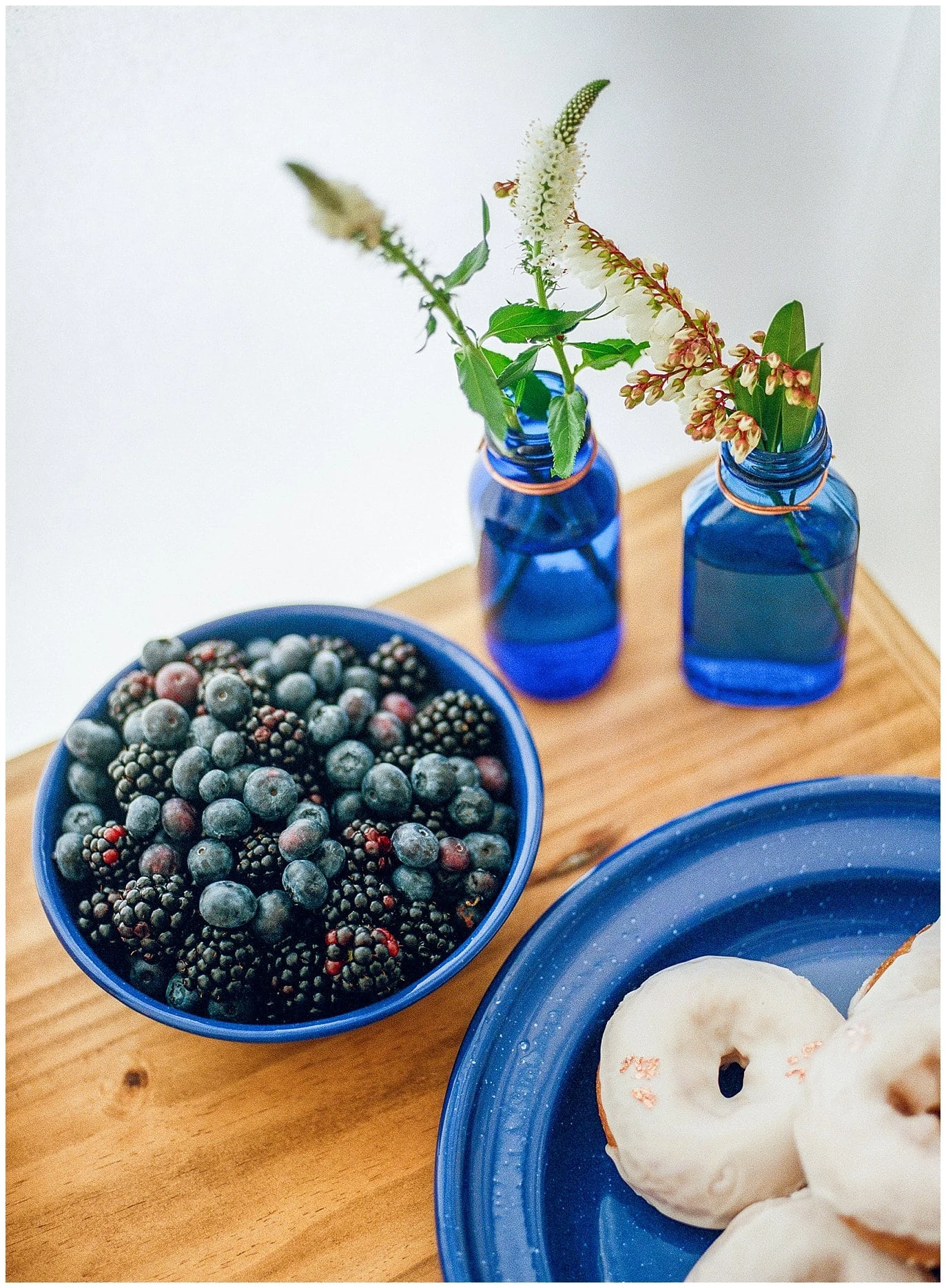 wedding glamping breakfast in bed with blueberries, glazed donuts, and blue metal plates