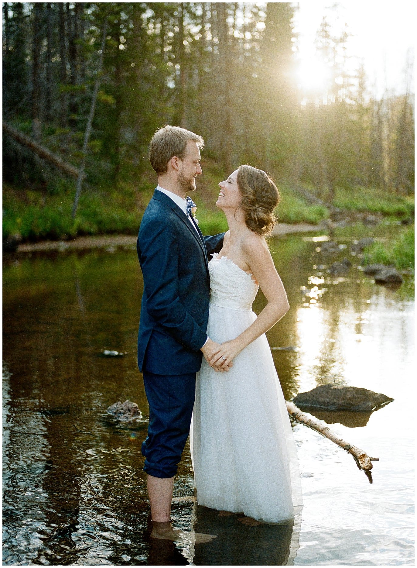 bride and groom wading in river on wedding day at Piney River Ranch intimate wedding by Beaver Creek wedding photographer Jennie Crate Photographer