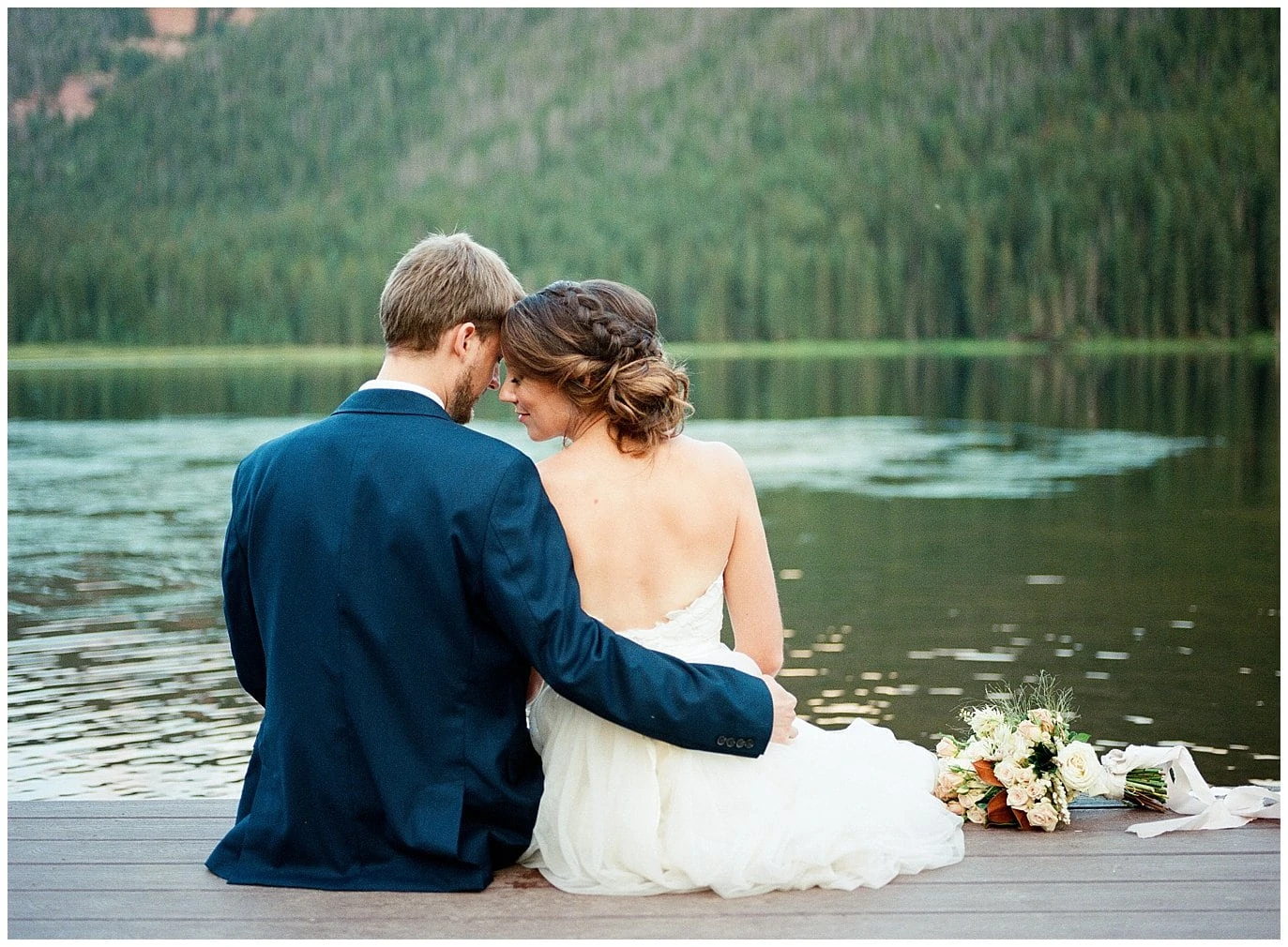 bride and groom cuddling on dock by alpine Colorado lake at Piney River Ranch intimate wedding by Aspen wedding photographer Jennie Crate Photographer