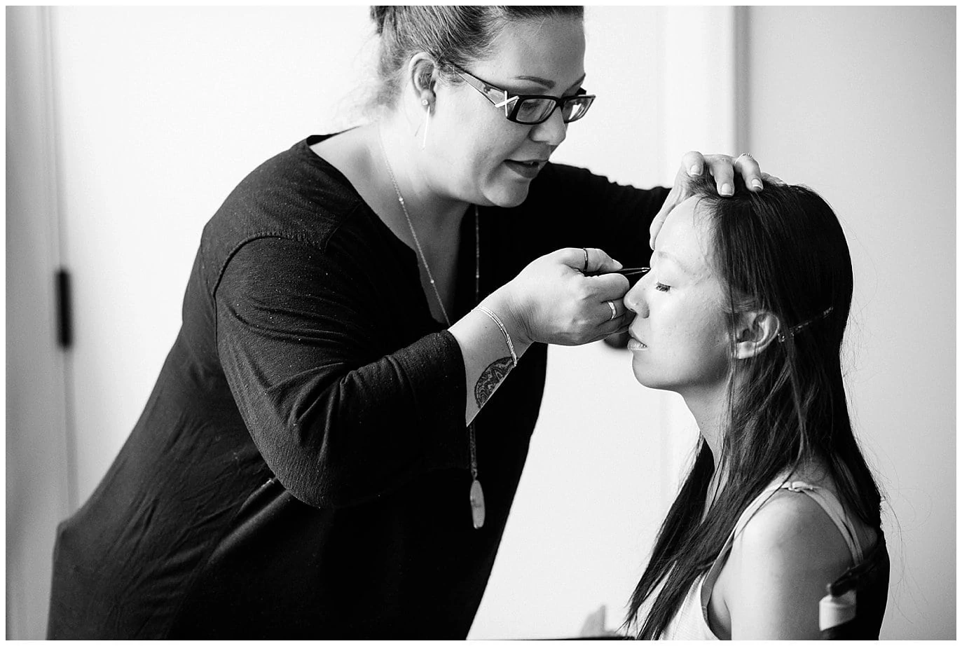 bride getting lashes done on wedding day photo