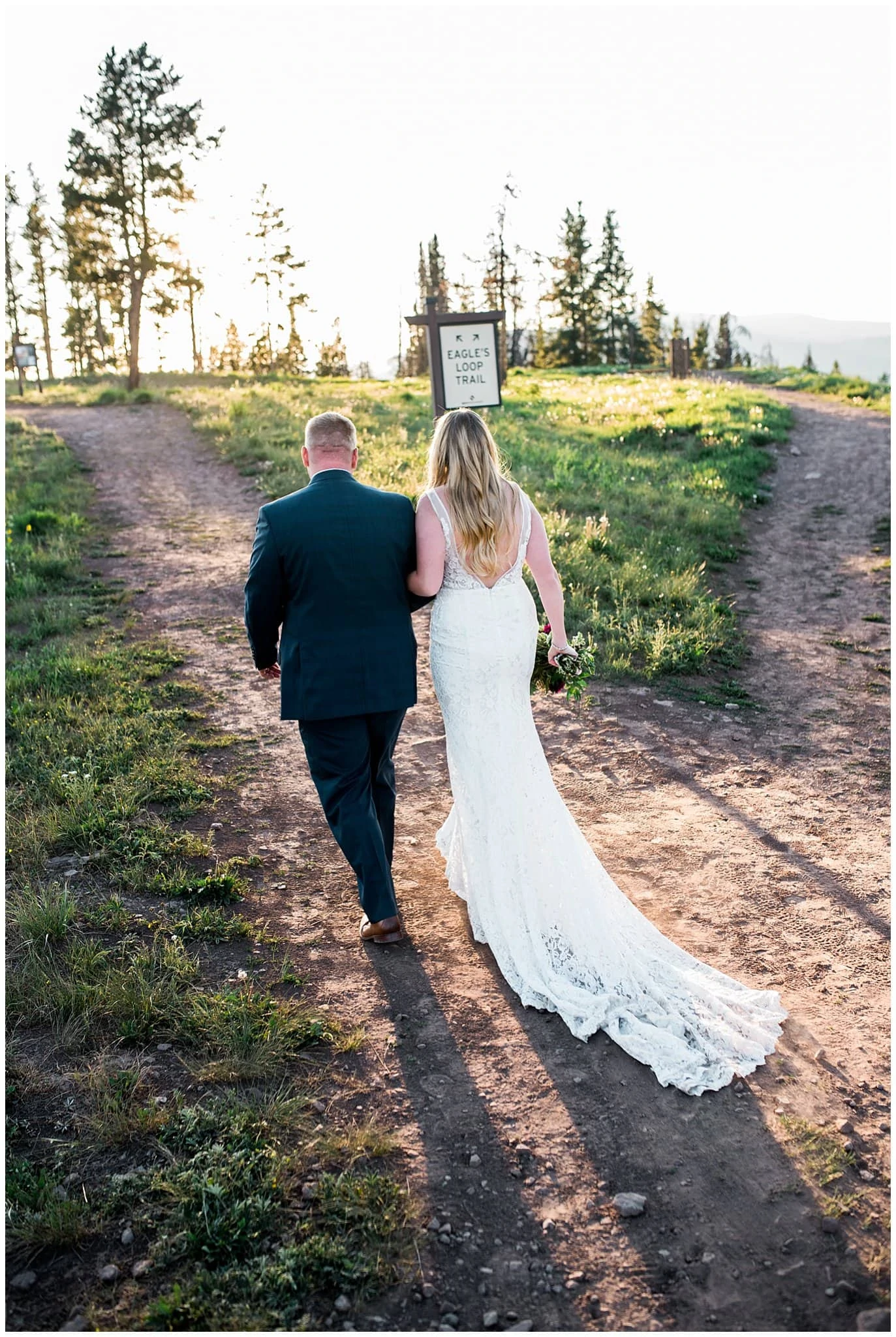 bride and groom walking on mountain at sunset photo