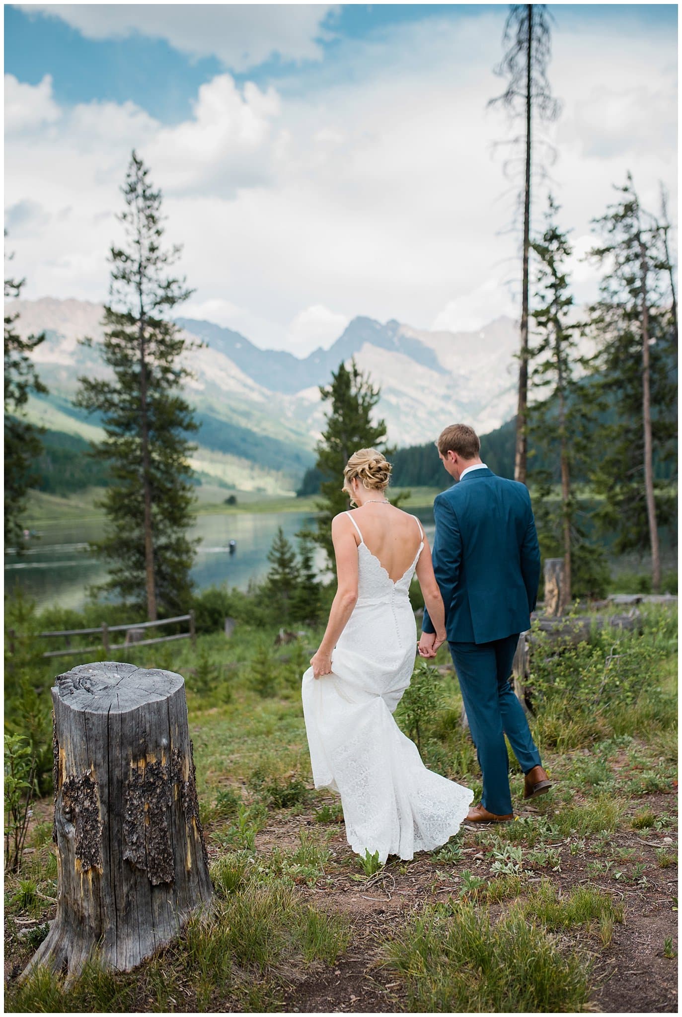 bride and groom walk hand in hand towards lake at Piney River Ranch Summer Wedding by Piney River Ranch wedding photographer Jennie Crate photographer
