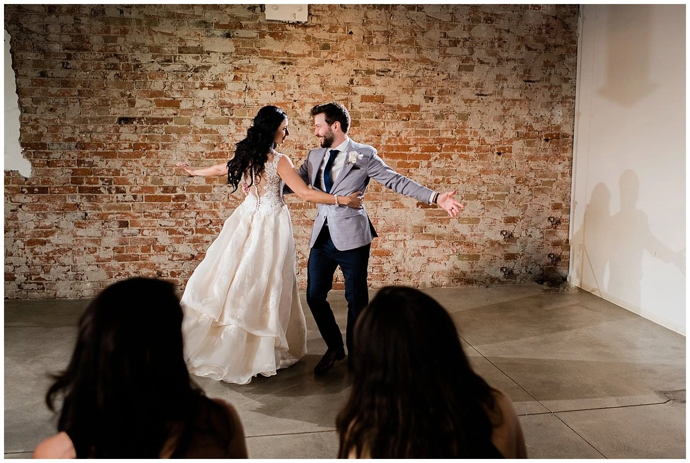 bride and groom dancing with brick wall at by Blanc Wedding Photographer Jennie Crate