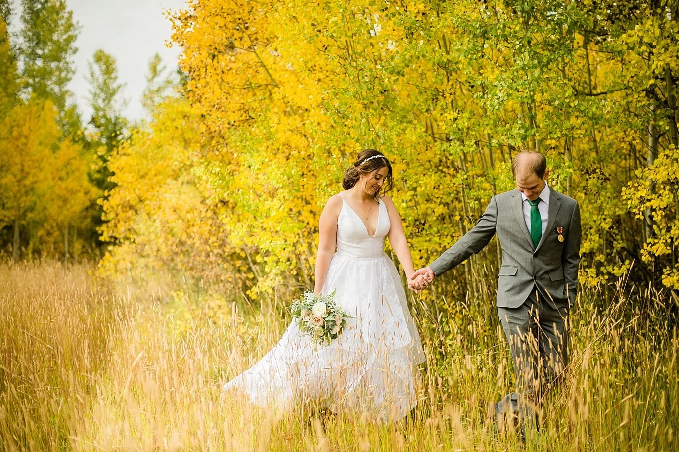 bride and groom walk in blazing yellow aspens at B Lazy 2 Ranch wedding by Winter Park wedding photographer Jennie Crate