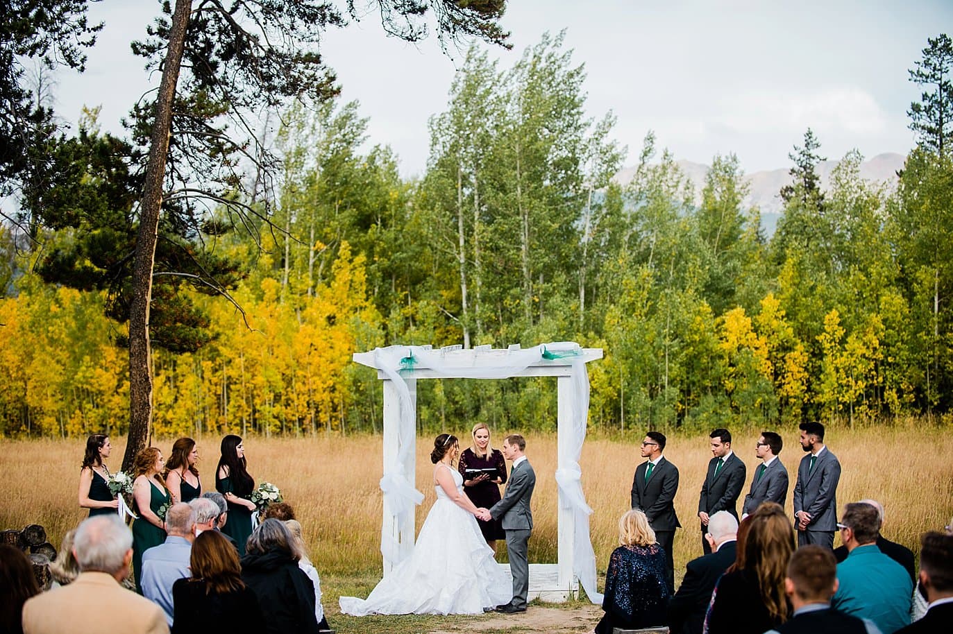 bride and groom at alter among fall yellow aspens at B Lazy 2 Ranch wedding by Fraser wedding photographer Jennie Crate