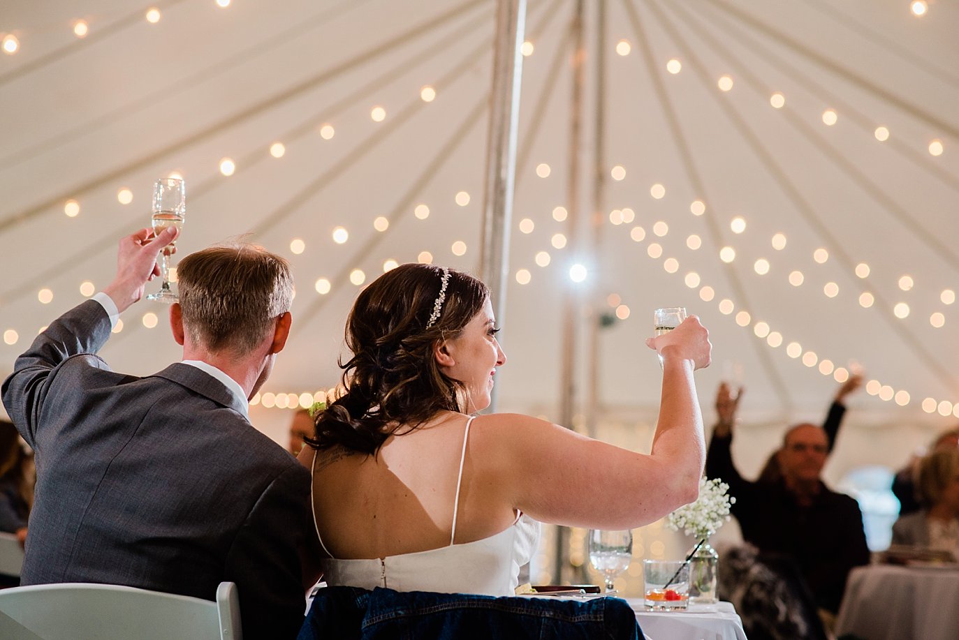 bride and groom cheers during toasts at B Lazy 2 Ranch wedding by Winter Park wedding photographer Jennie Crate