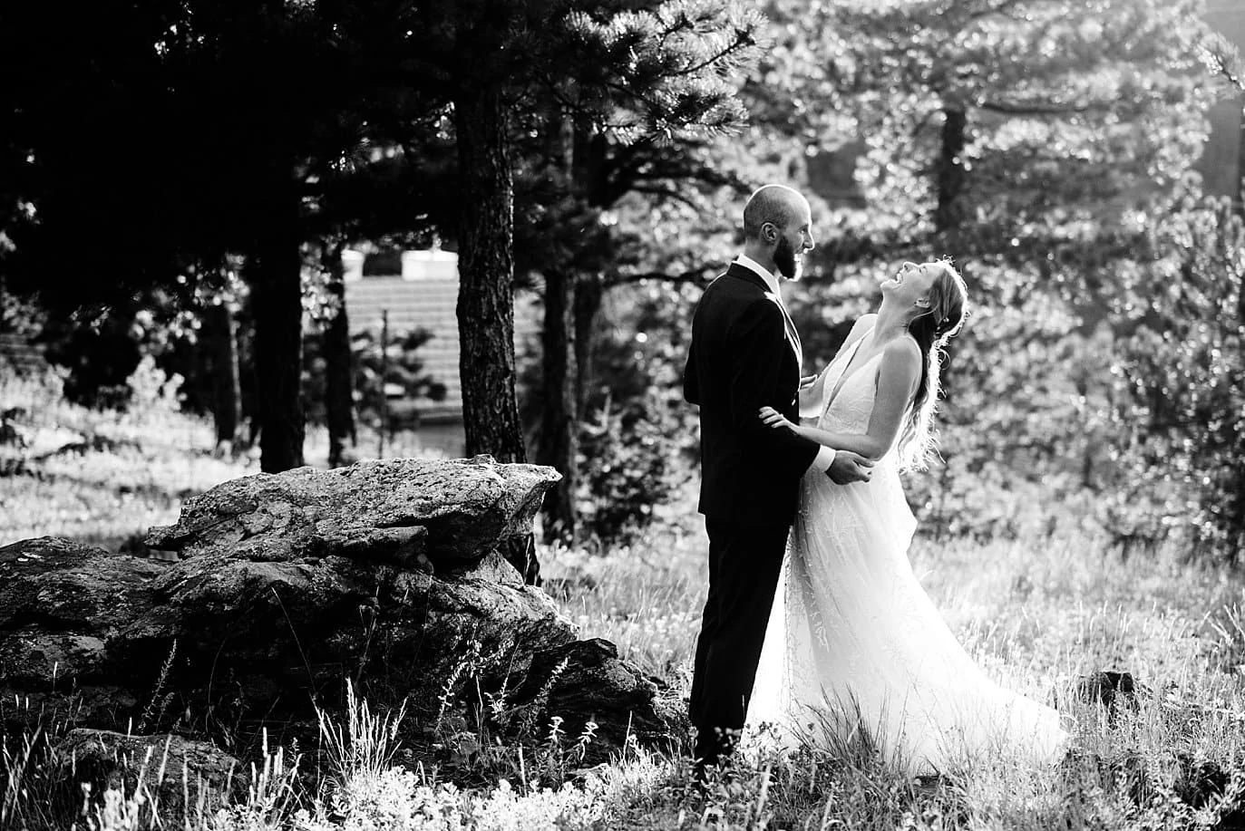 black and white photo of bride laughing in the trees at sunset colorado wedding