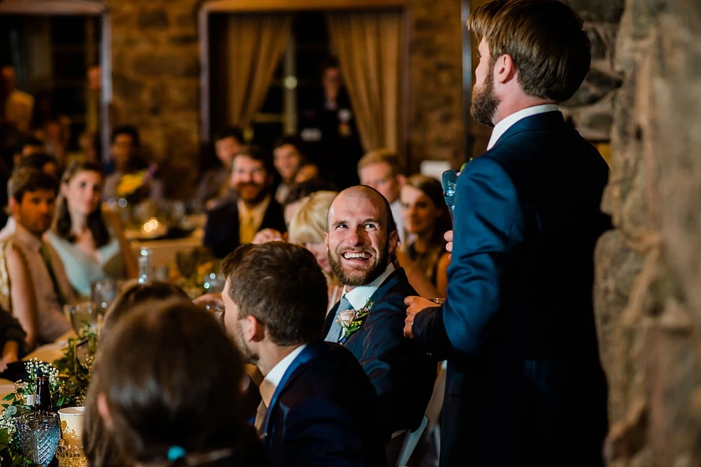 groom laughing during best man speech wedding reception