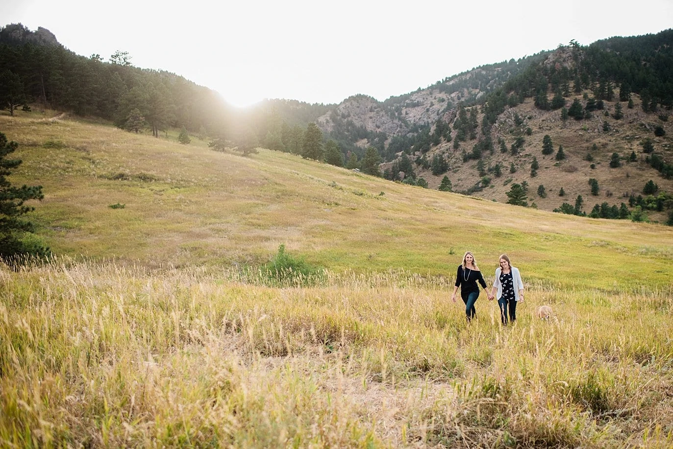 lesbian couple walks through field Chautaqua Park engagement by Boulder engagement photographer Jennie Crate
