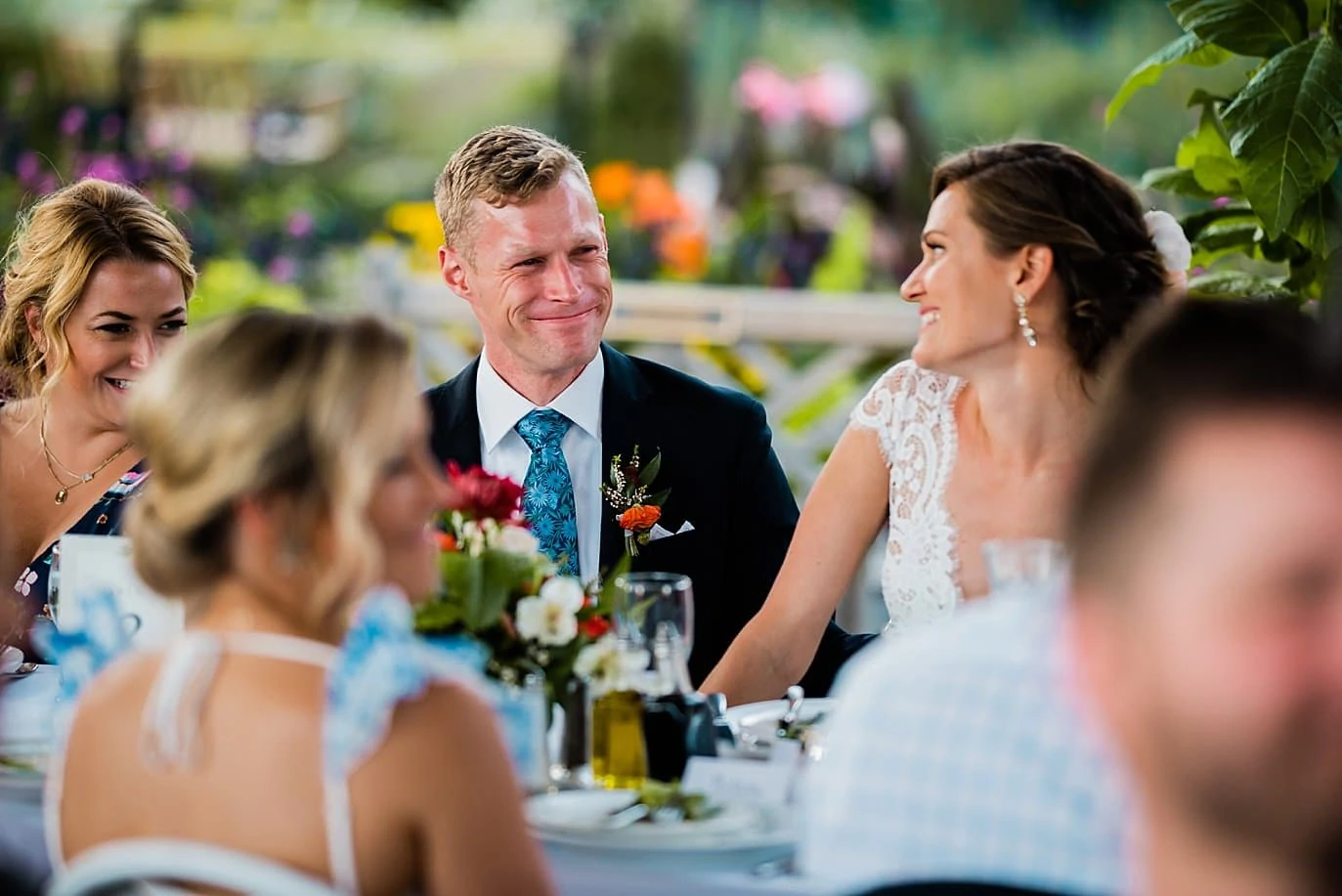 bride and groom smiling at each other during toasts in Annuals garden at Denver Botanic Gardens wedding by Aurora Wedding Photographer Jennie Crate