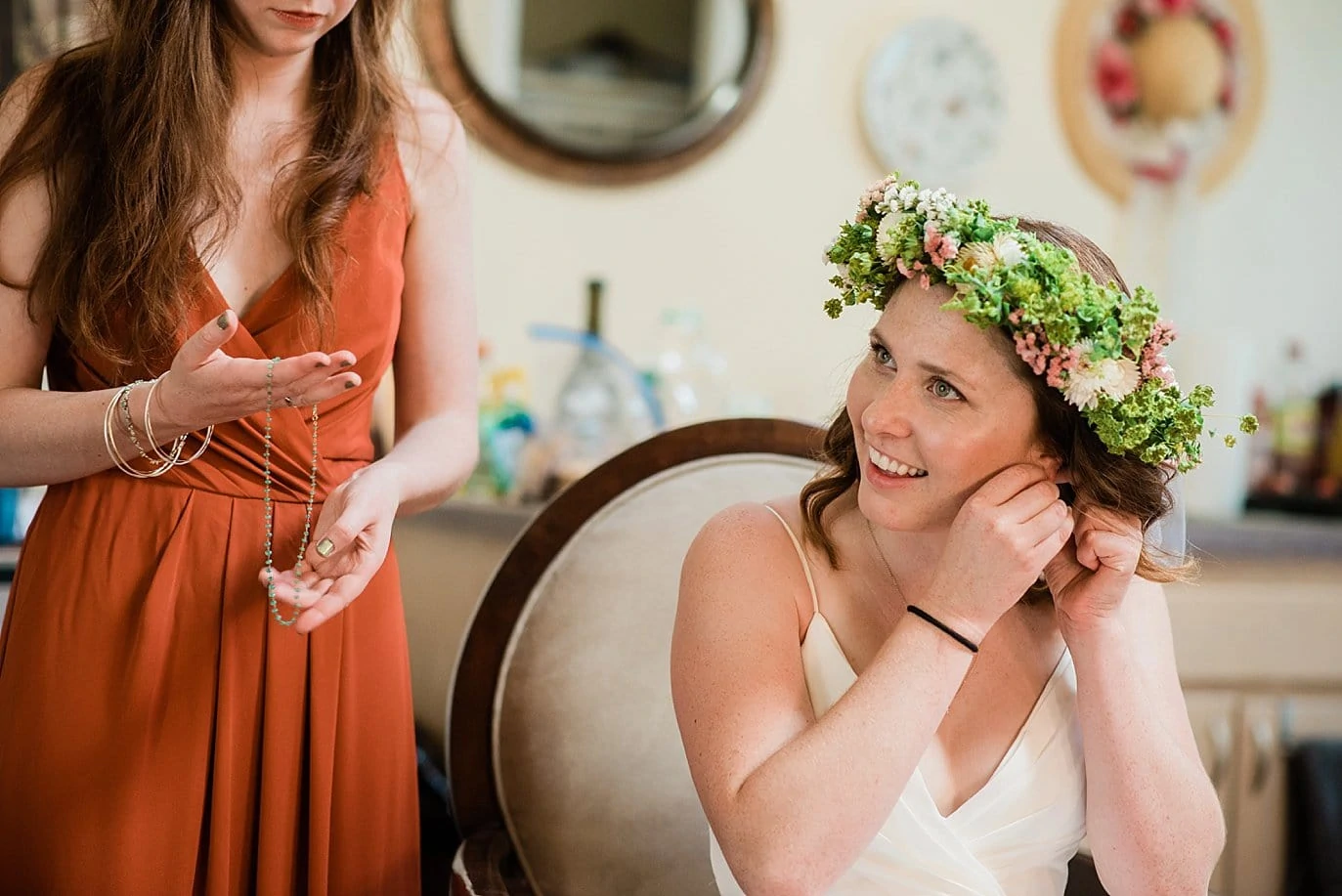 bride in flower crown putting on jewelry on colorado wedding day photo