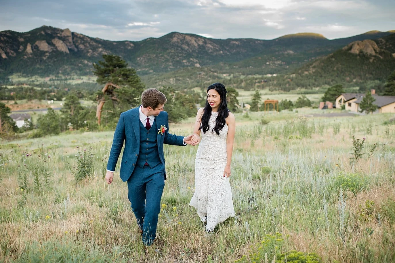 Bride and groom walking by lodge at Rocky Mountain National Park Wedding by Denver Wedding Photographer Jennie Crate