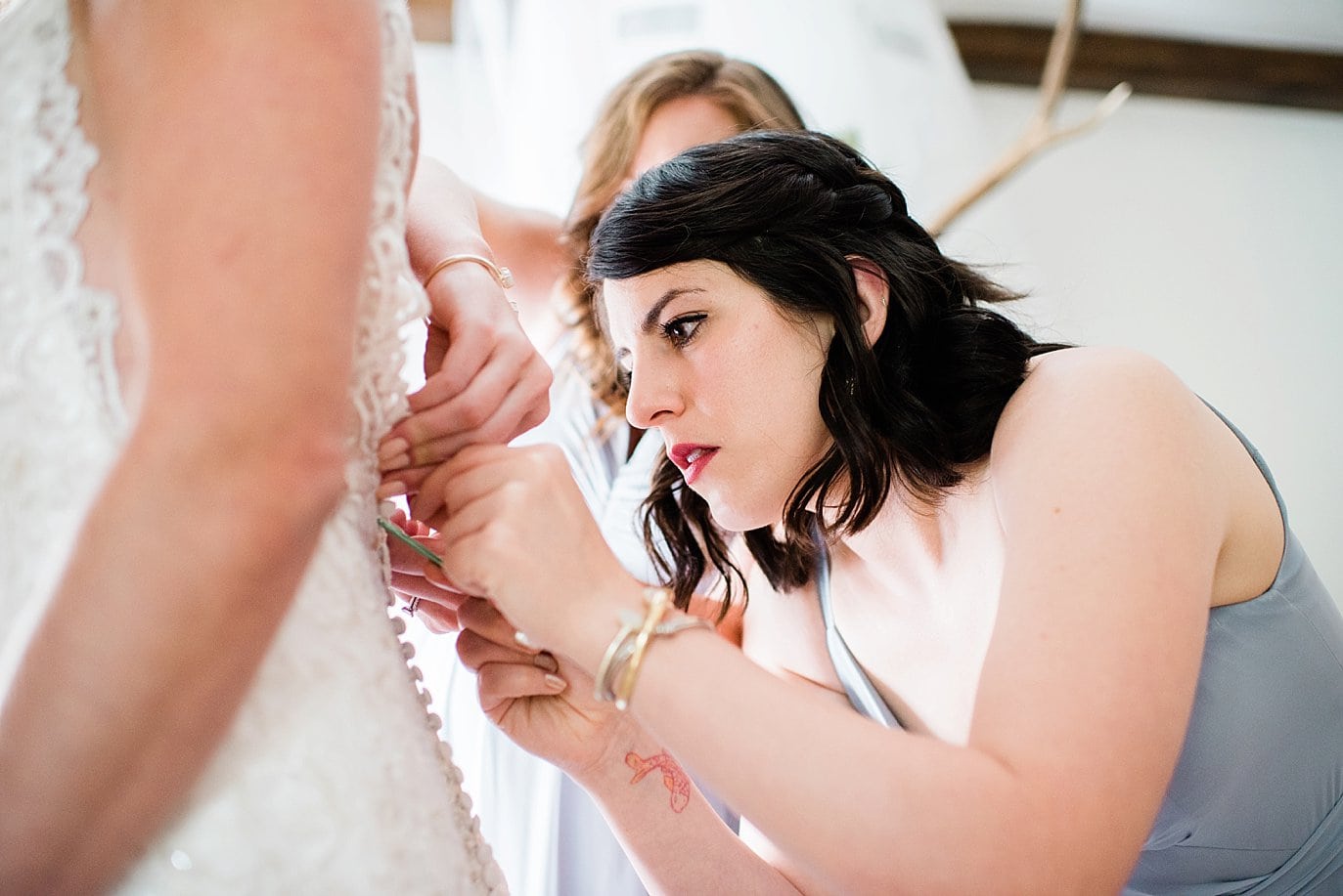 Bride getting dressed with bridesmaid help at Sonnenalp Hotel by Avon wedding photographer Jennie Crate
