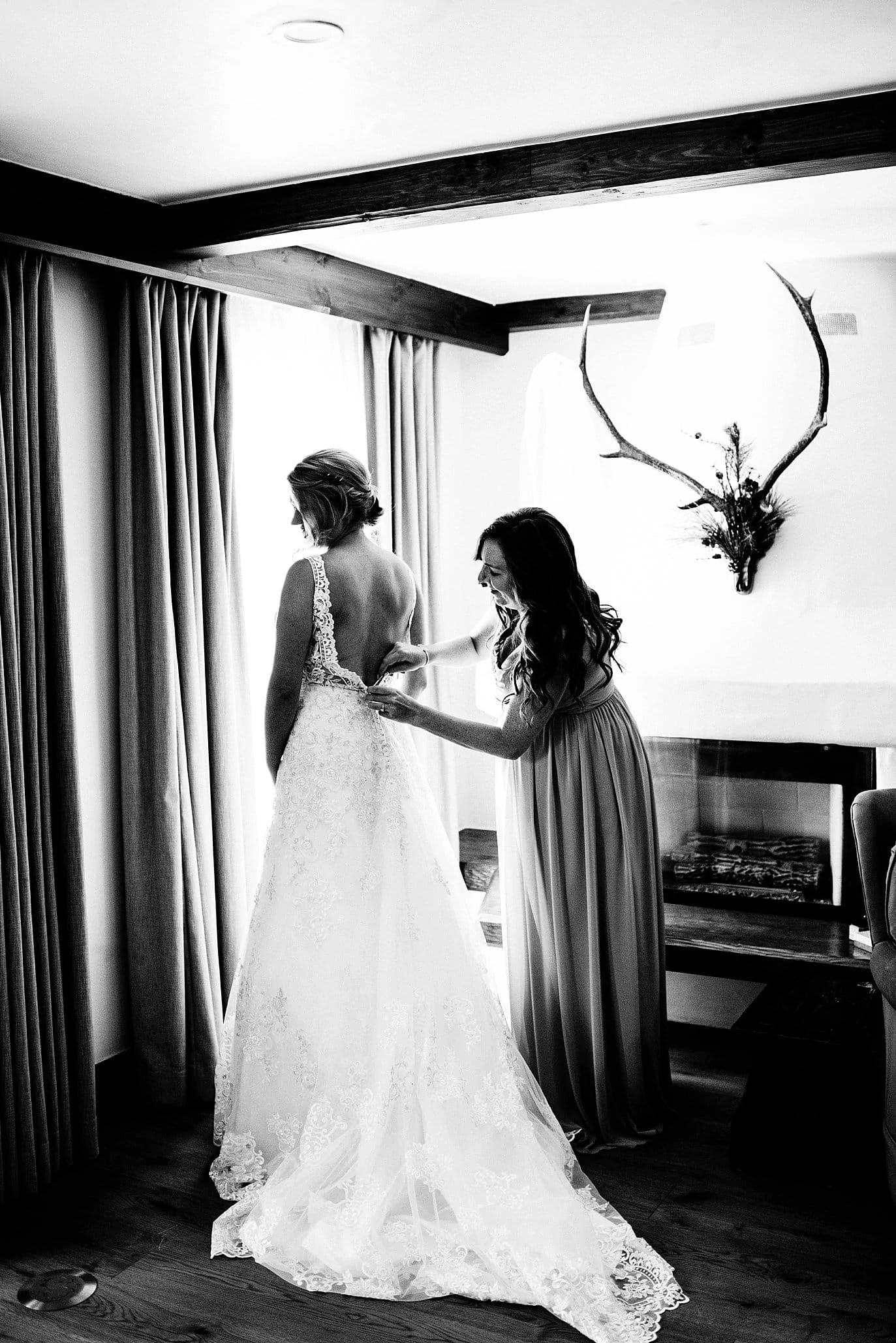 Bride getting dressed by window at Sonnenalp Hotel by Eagle wedding photographer Jennie Crate