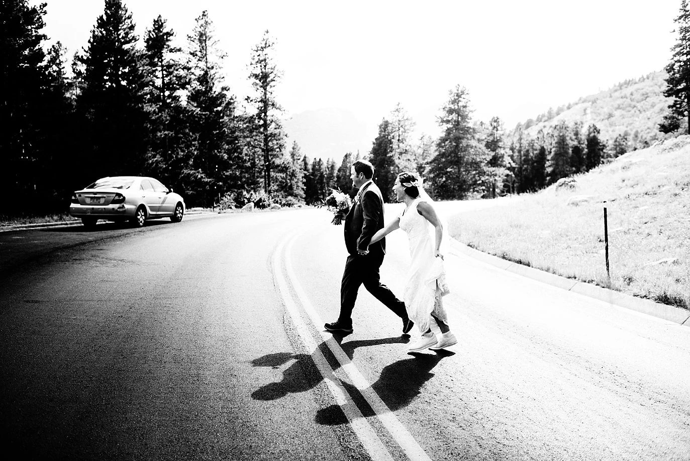 couple running across the road at Rocky Mountain National Park wedding by Estes Park wedding photographer Jennie Crate