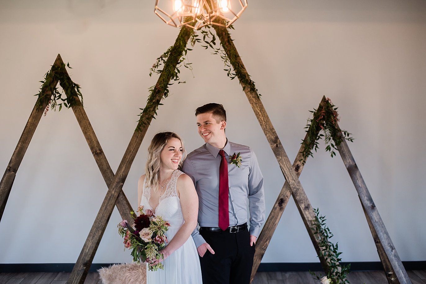 bride and groom in front of wooden mountain ceremony arch at Northgate Event Center wedding by Thornton wedding photographer Jennie Crate
