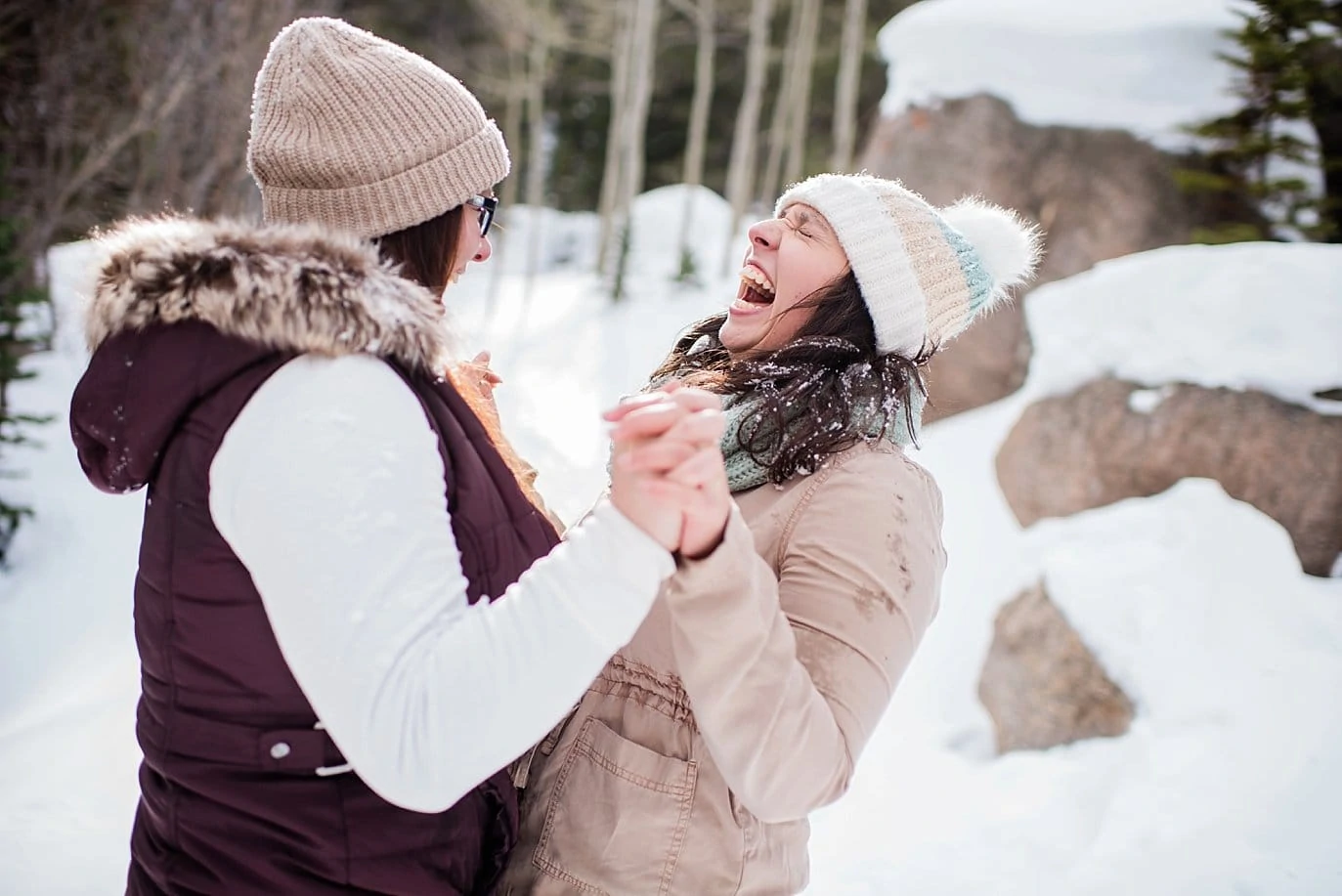 queer couple laughing in snow Alberta Falls Rocky Mountain National Park winter hiking engagement by Denver engagement photographer Jennie Crate, Photographer