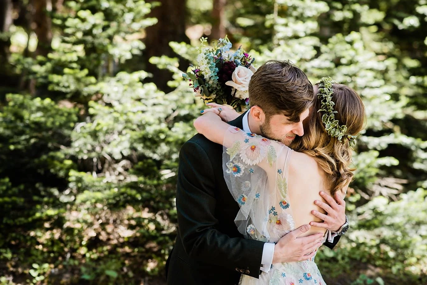 bride and groom embrace after first look in trees at Arapahoe Basin wedding by Breckenridge wedding photographer Jennie Crate