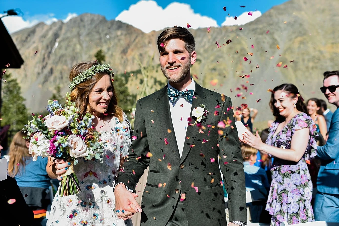 bride and groom leave ceremony in shower of flower petals at Arapahoe Basin wedding by Vail wedding photographer