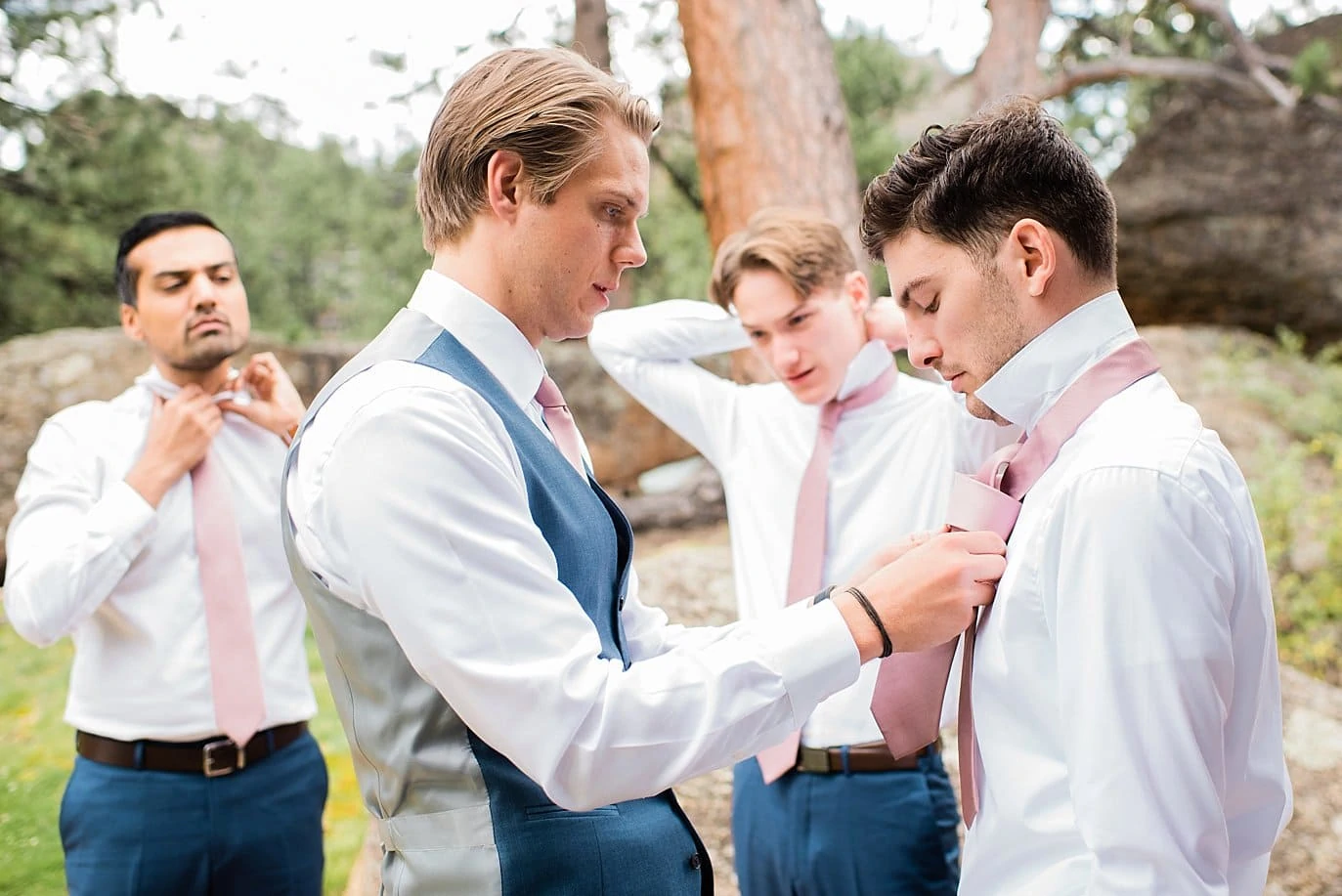groom and groomsmen tying ties outdoors at Black Canyon Inn wedding by Estes Park wedding photographer Jennie Crate Photographer