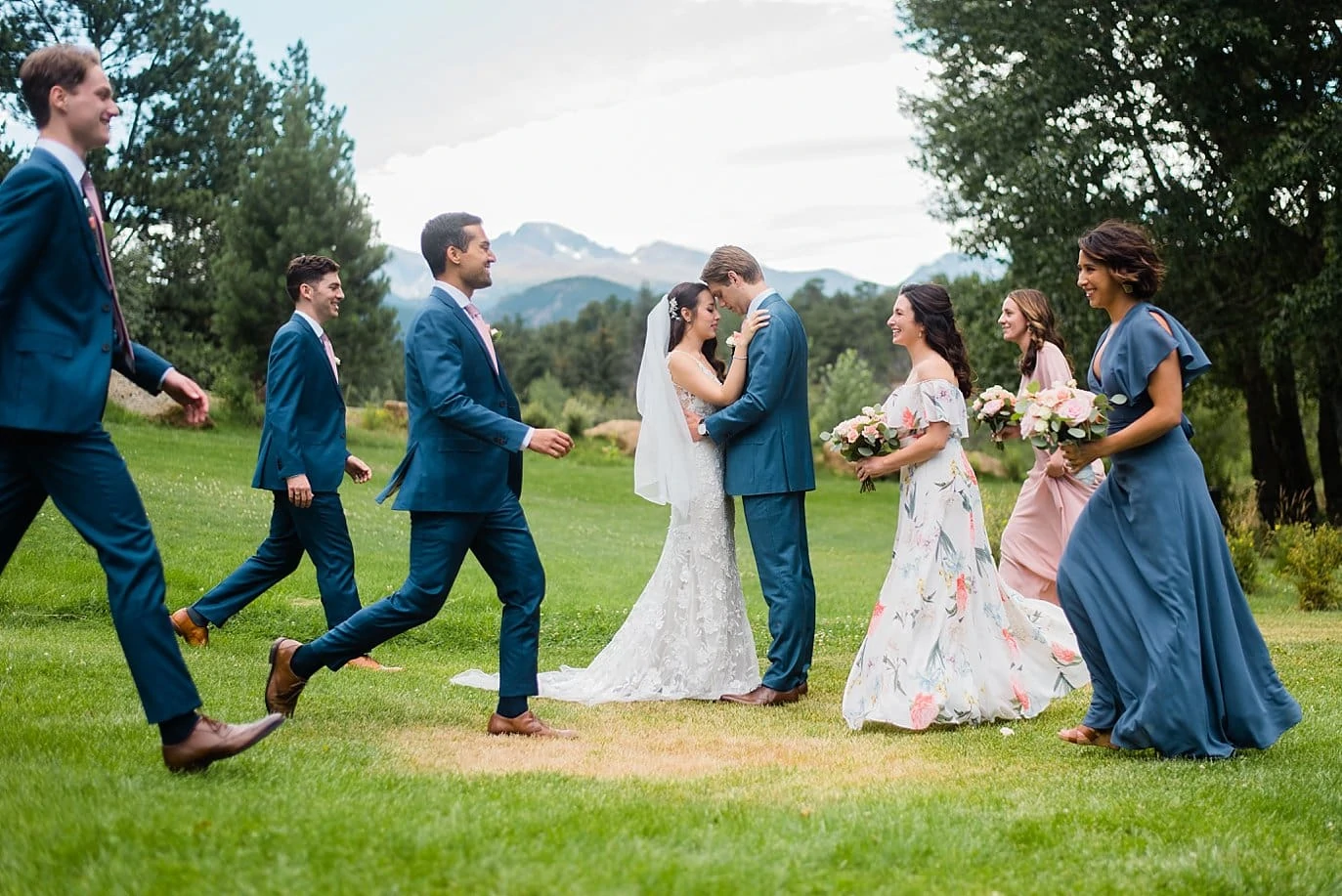 bride and groom kiss while bridal party walks by at Black Canyon Inn wedding by Estes Park wedding photographer Jennie Crate Photographer