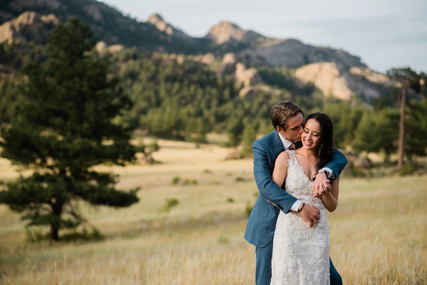 bride and groom cuddle at sunset in field in Estes Park at t Twin Owls Steakhouse wedding by Boulder wedding photographer Jennie Crate photographer