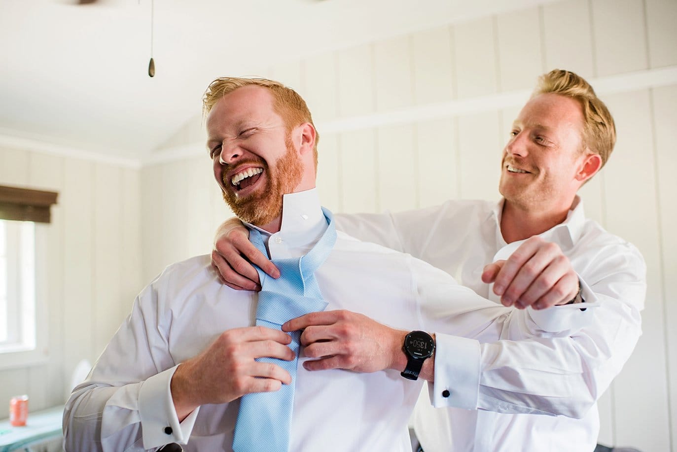 groomsmen tying tie of groom in cabin while getting ready at Grand Lake Lodge wedding by RMNP wedding photographer Jennie Crate