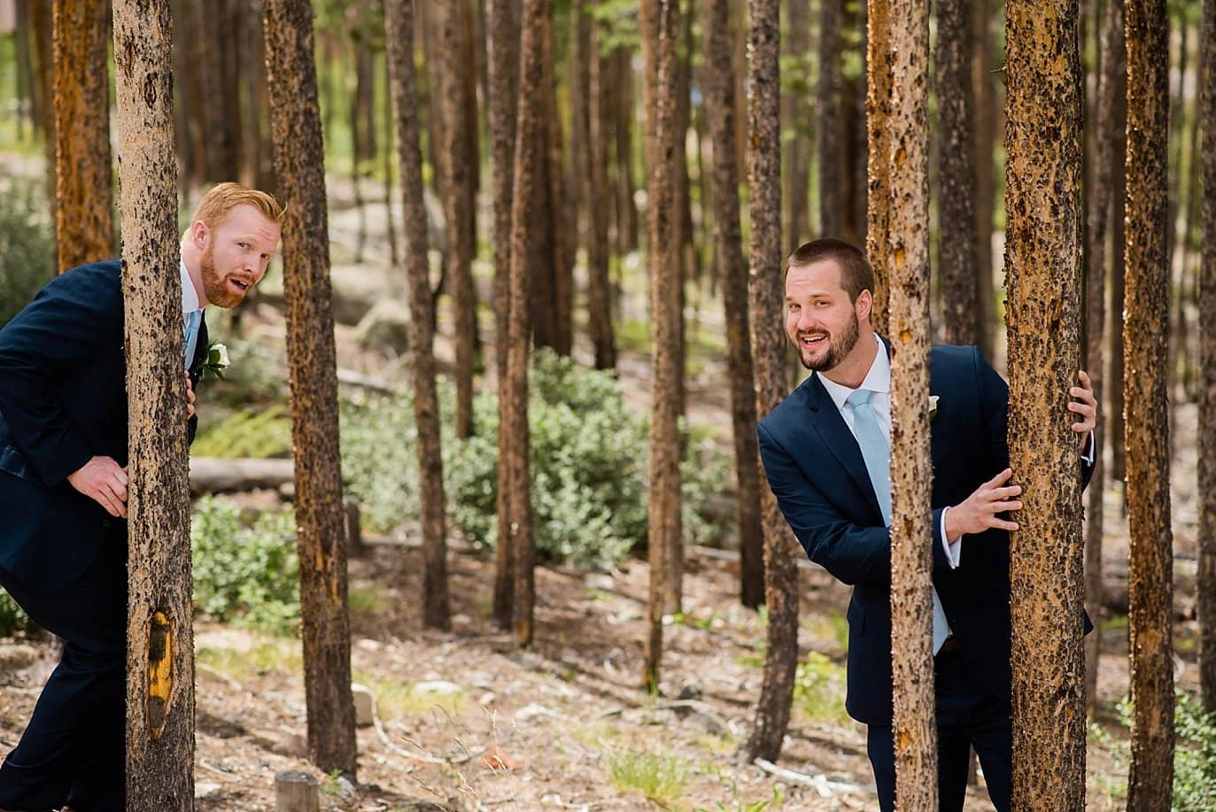 groom and groomsmen playing in evergreen trees around cabin at Grand Lake Lodge wedding by RMNP wedding photographer Jennie Crate