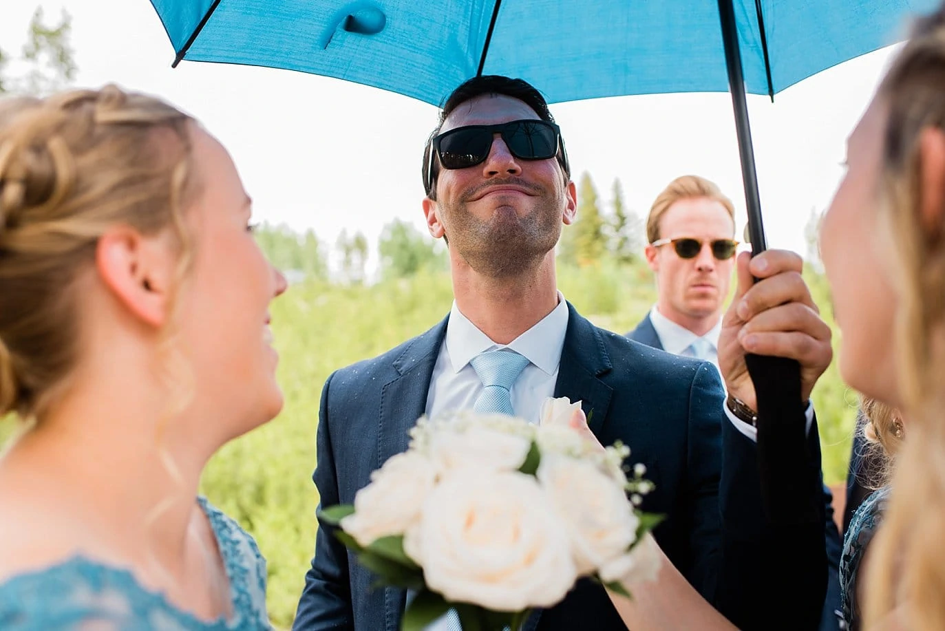 groomsmen takes cover under umbrella at Grand Lake Lodge wedding by Boulder wedding photographer Jennie Crate