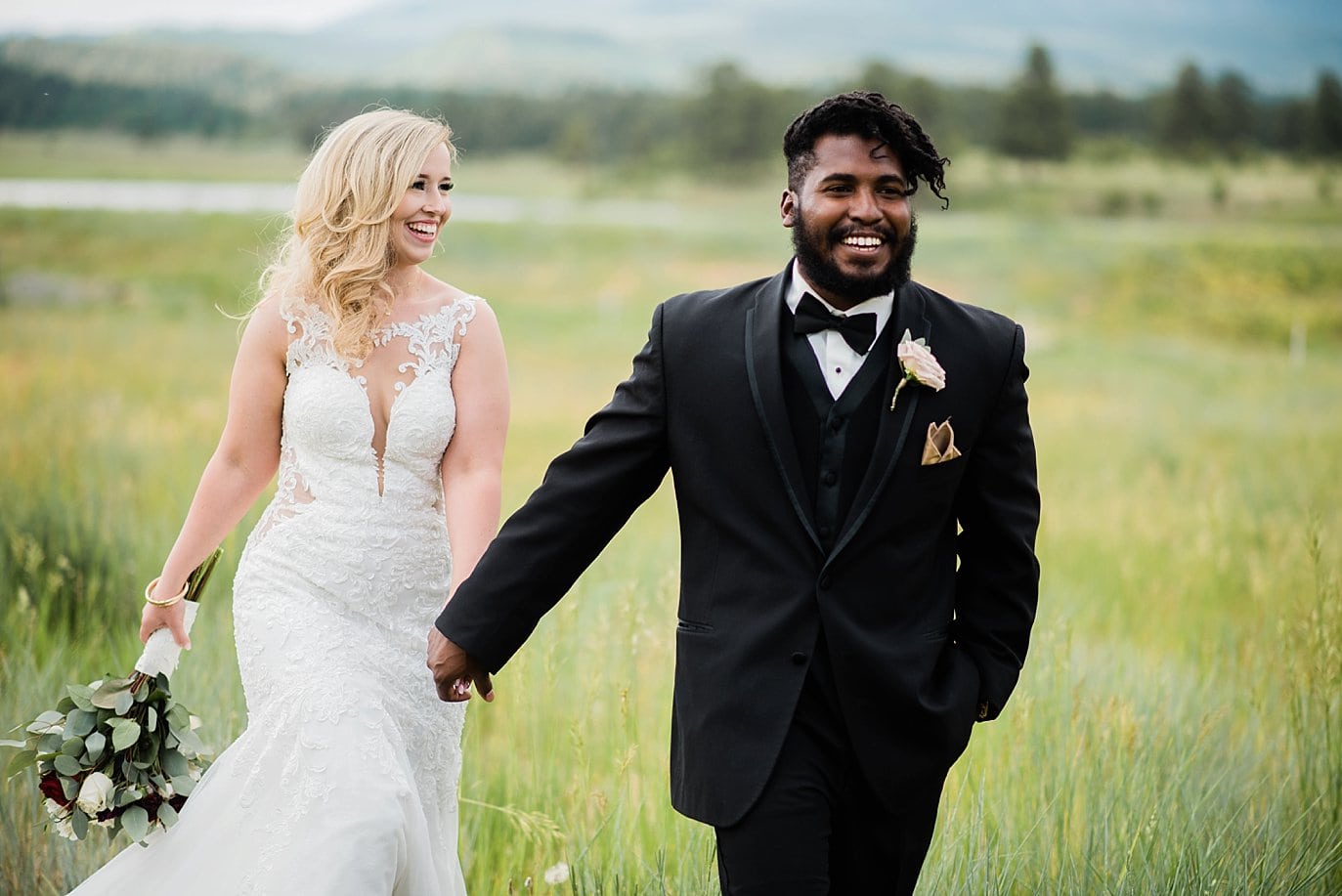 bride and groom walk hand in and in field at Pagosa Springs wedding by Aspen Wedding Photographer Jennie Crate