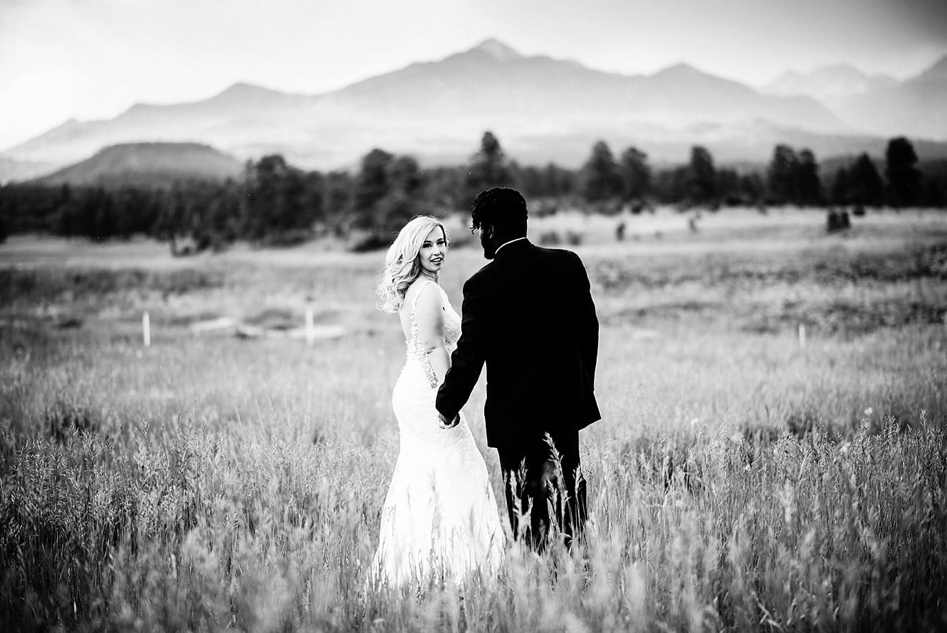 black and white photo of bride and groom in field with mountains in the background at Pagosa Springs wedding by Aspen Wedding Photographer Jennie Crate