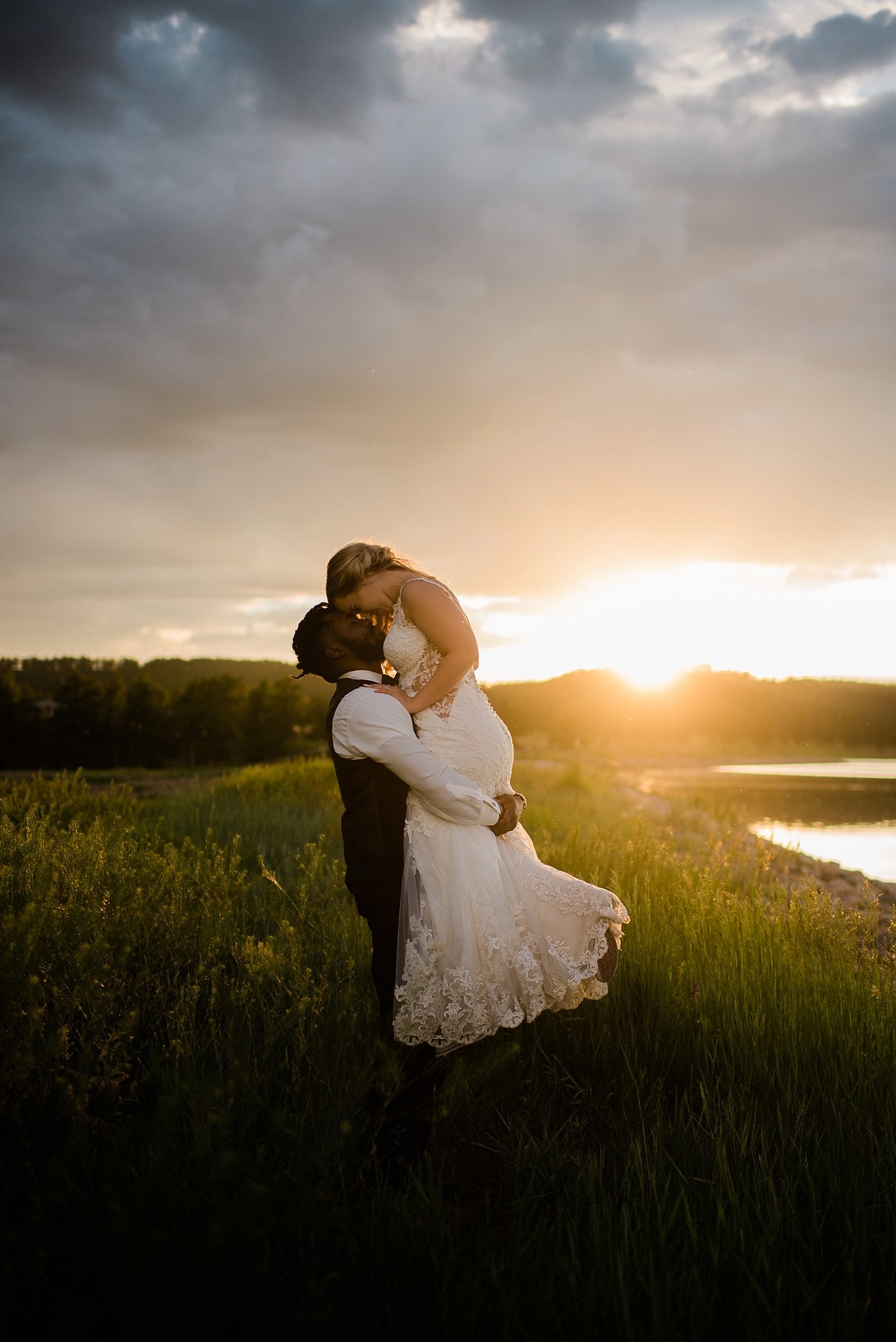 groom lifts bride by lake at sunset portrait at at Pagosa Springs wedding by Pagosa Springs Wedding Photographer Jennie Crate