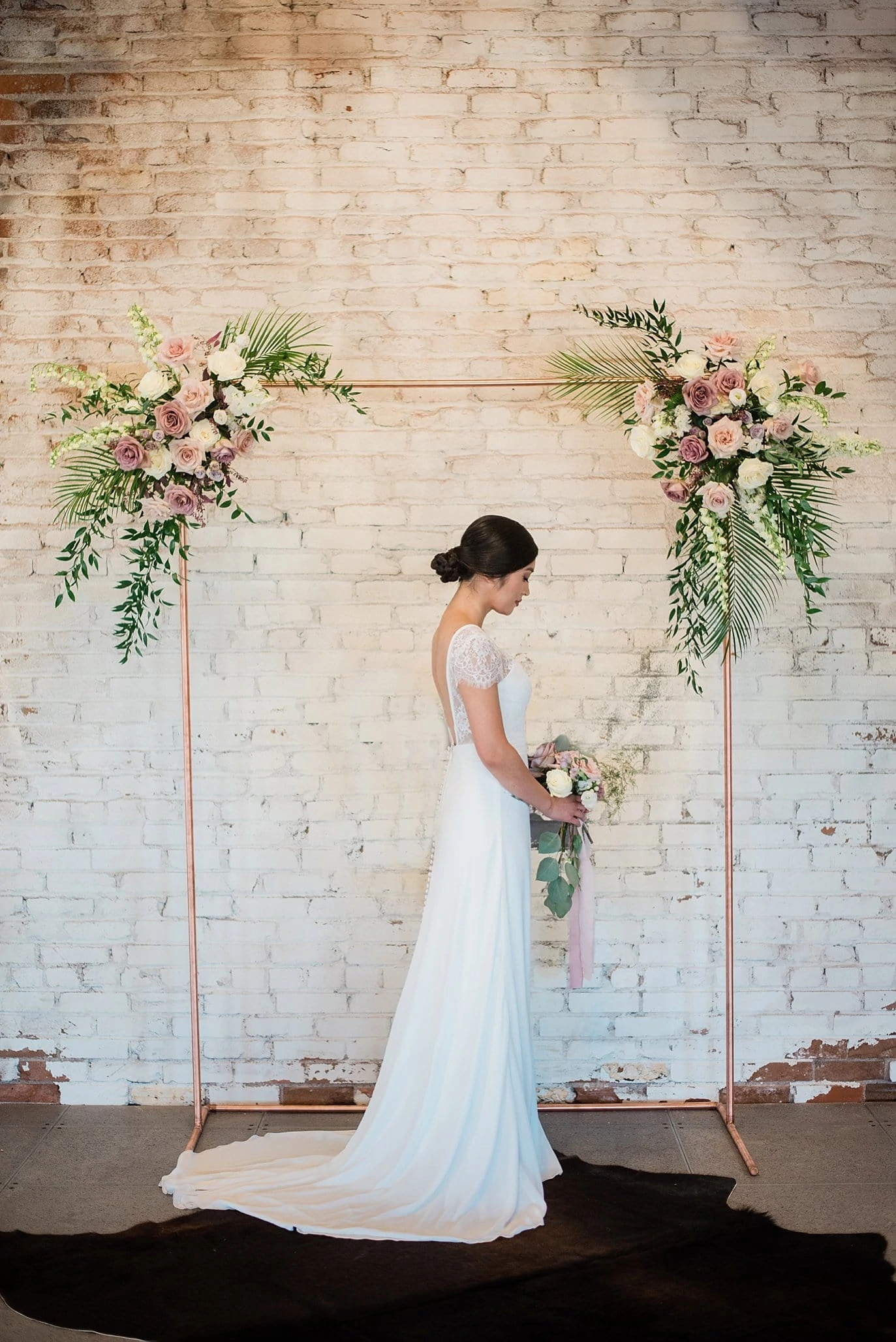 bride in front of copper ceremony arch decorated with rose and violet flowers and green ferns at Shyft Denver wedding by Boulder Wedding photographer Jennie Crate photographer