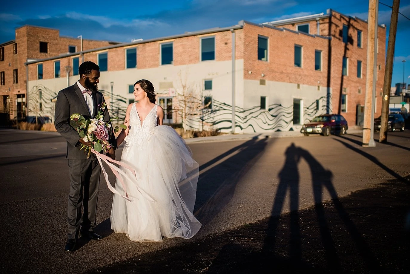 bride and groom walking by STEAM on the Platte building at Shyft Denver wedding by Aurora wedding photographer Jennie Crate photographer
