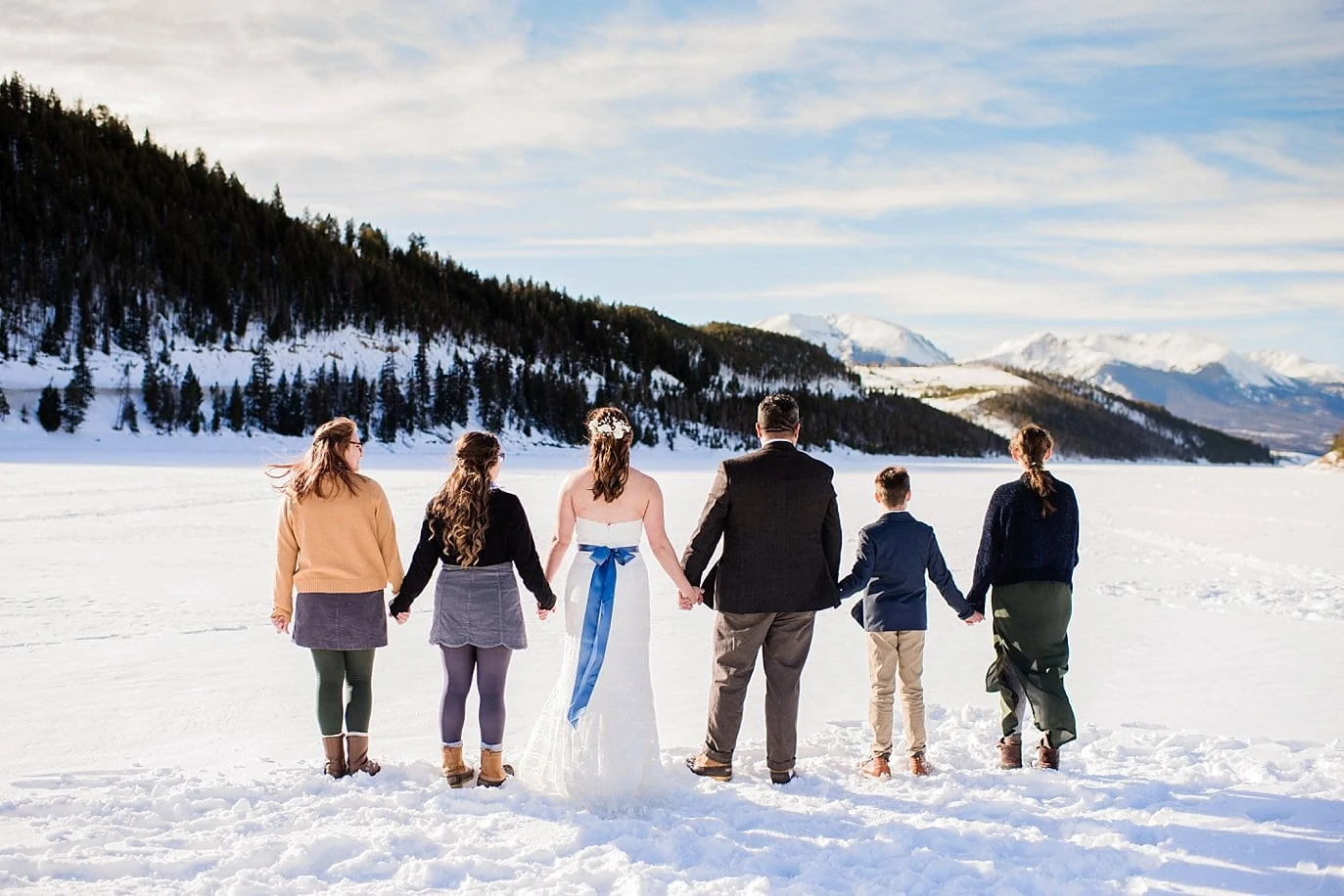 bride and groom and family hold hands on Lake Dillon at Sapphire Point Elopement by Vail wedding photographer Jennie Crate Photographer