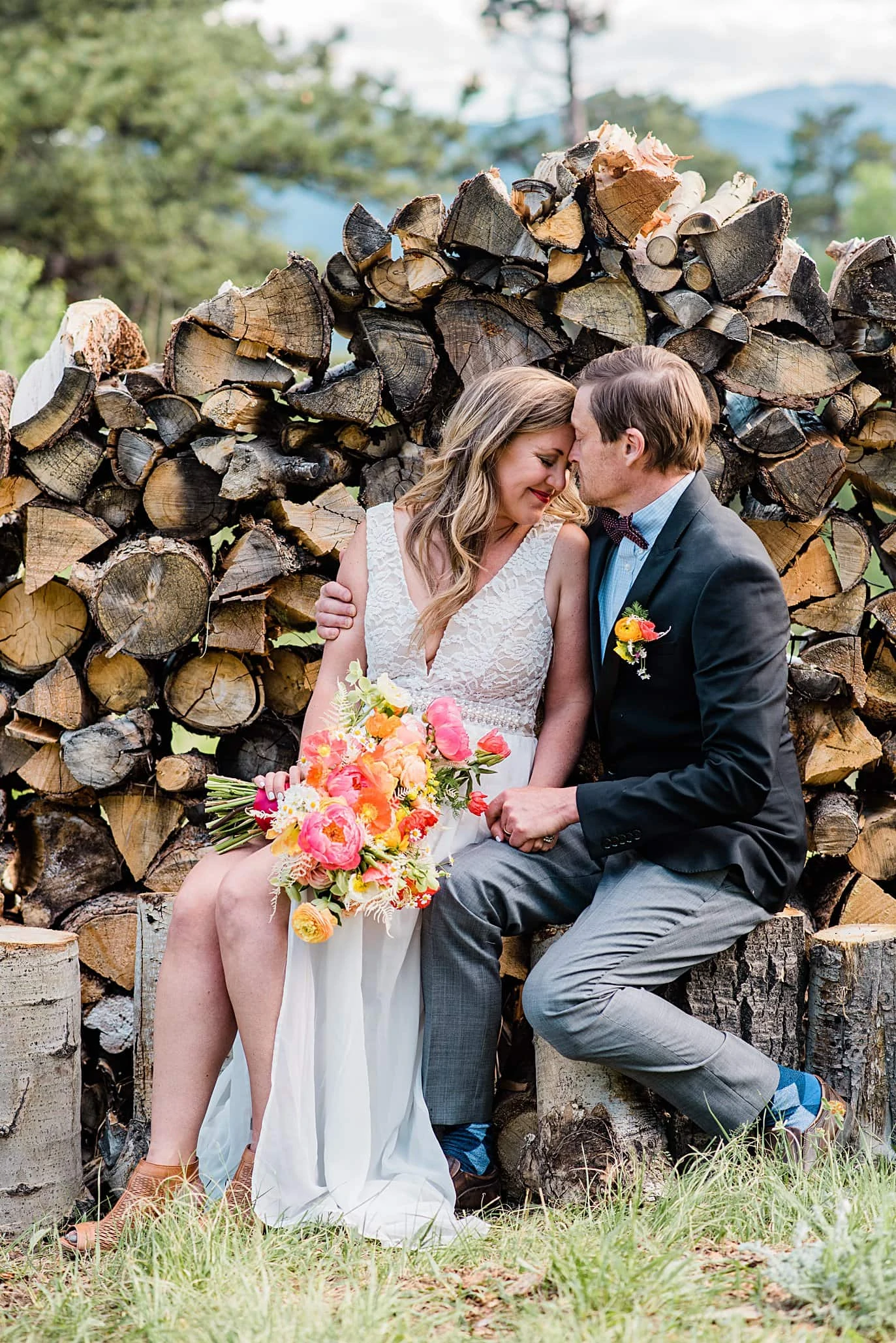 bride and groom cuddle by split log firewood pile at private property Golden elopement by Golden wedding photographer Jennie Crate