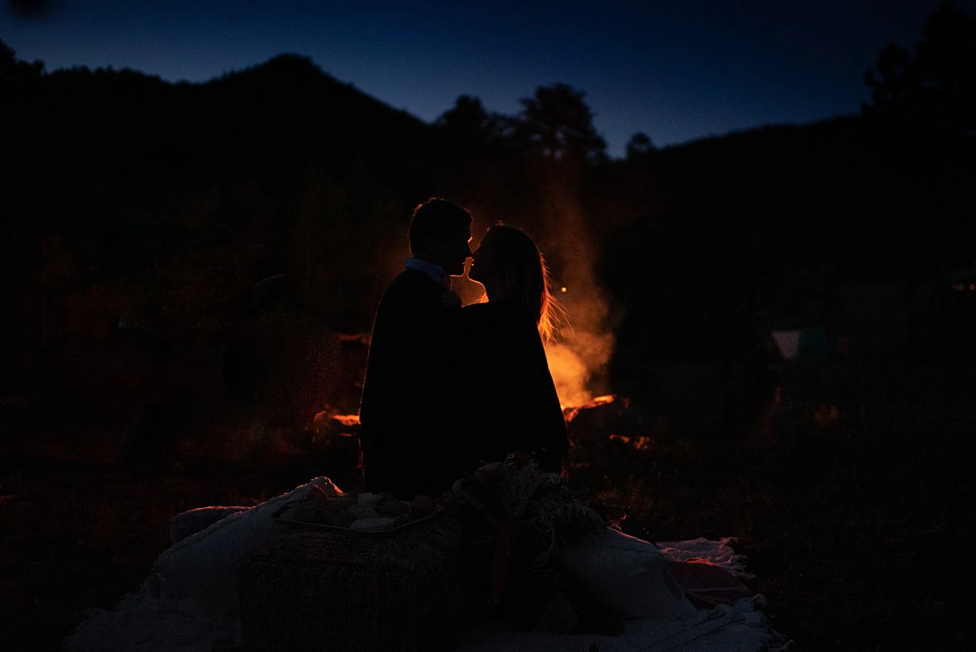 couple cuddled by firepit at private Golden elopement by Boulder wedding photographer Jennie Crate