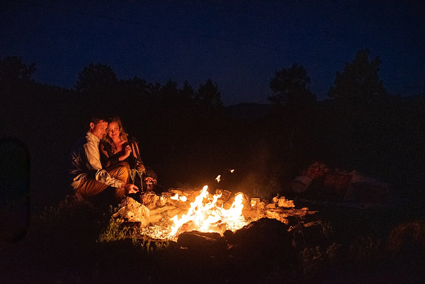 couple cuddles by fire at private Golden elopement by Boulder wedding photographer Jennie Crate