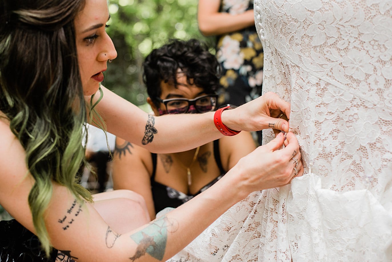 bride gets lace dress bustled by friends at Denver Botanic Gardens wedding by Denver Wedding Photographer Jennie Crate