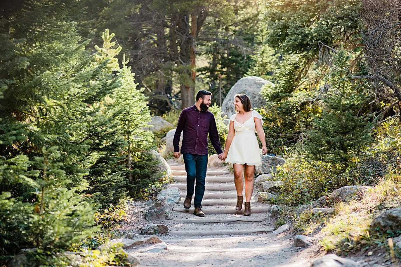 couple walking down trail at Alberta falls engagement session by Estes Park engagement photographer Jennie Crate