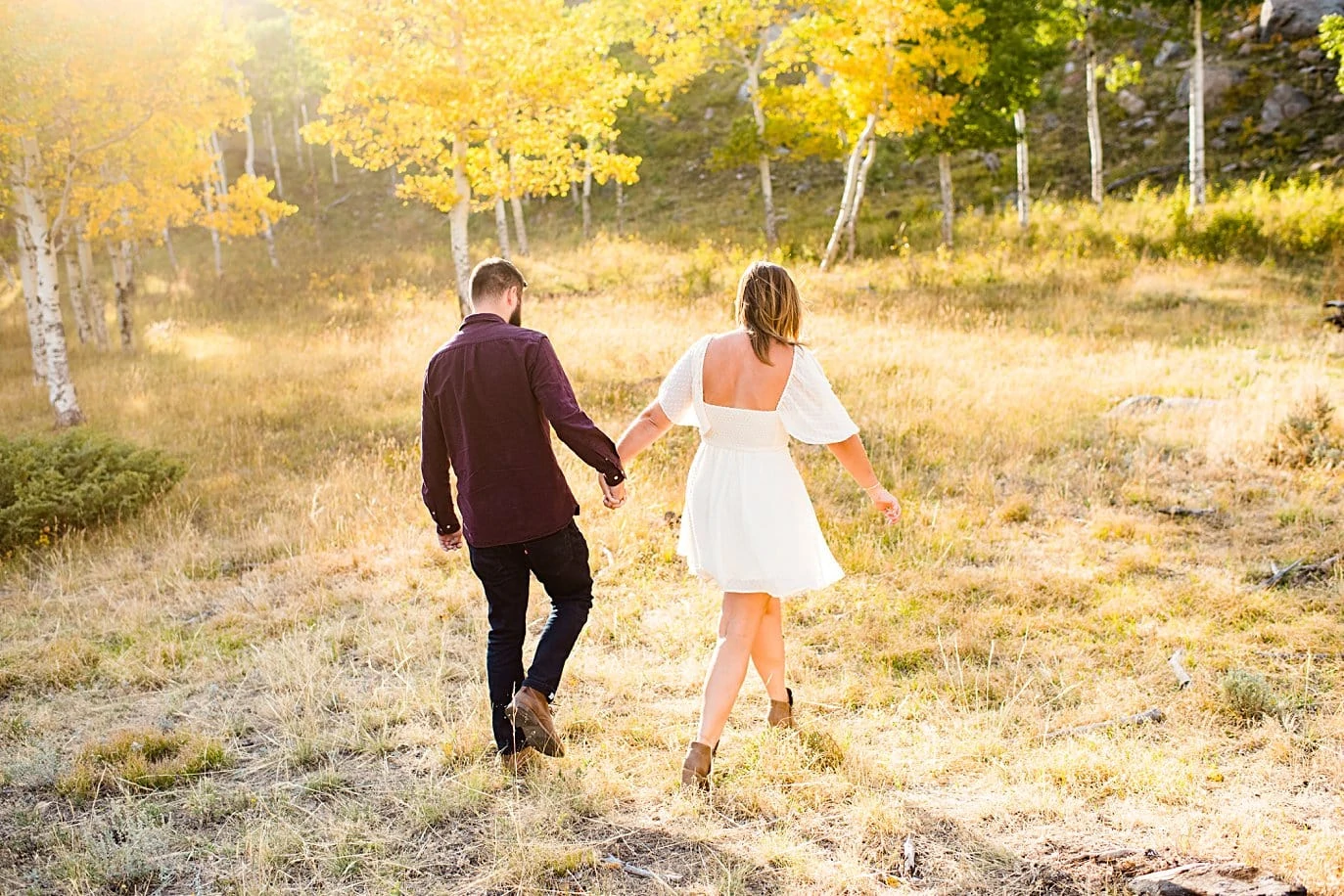 engaged couple walks in aspen grove in fall at RMNP engagement session by Estes Park engagement photographer Jennie Crate